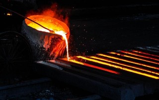 Hot molten metal being poured into long, thin cast.