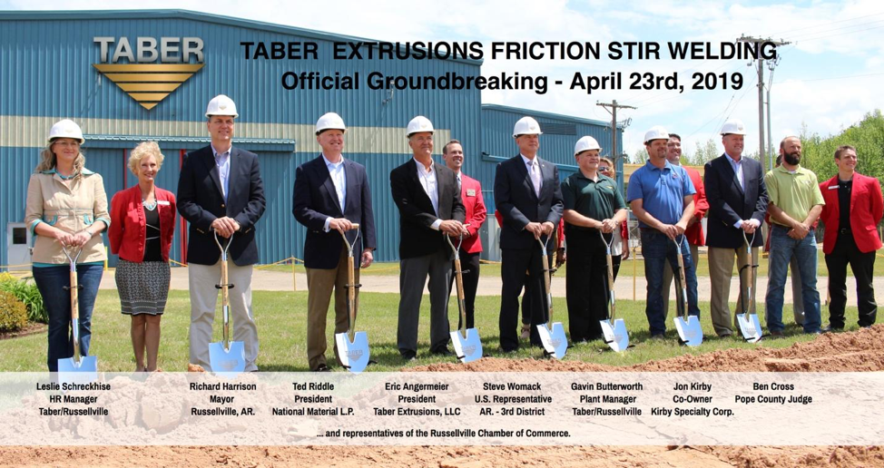 Individuals at Taber’s groundbreaking ceremony, sporting white hardhats and posing with shovels on a sunny day at the Taber Extrusions Russellville, Arkansas facility.