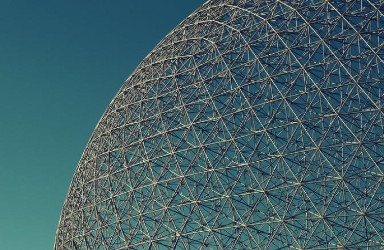 Looking up at the giant lattice-shell steel art structure known as the “Geodesic Dome” outside Montreal environmental museum “The Biosphere” on a clear blue skied day.