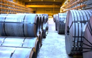 A warehouse with 2 rows of banded flat rolled steel stretching to the far back wall.