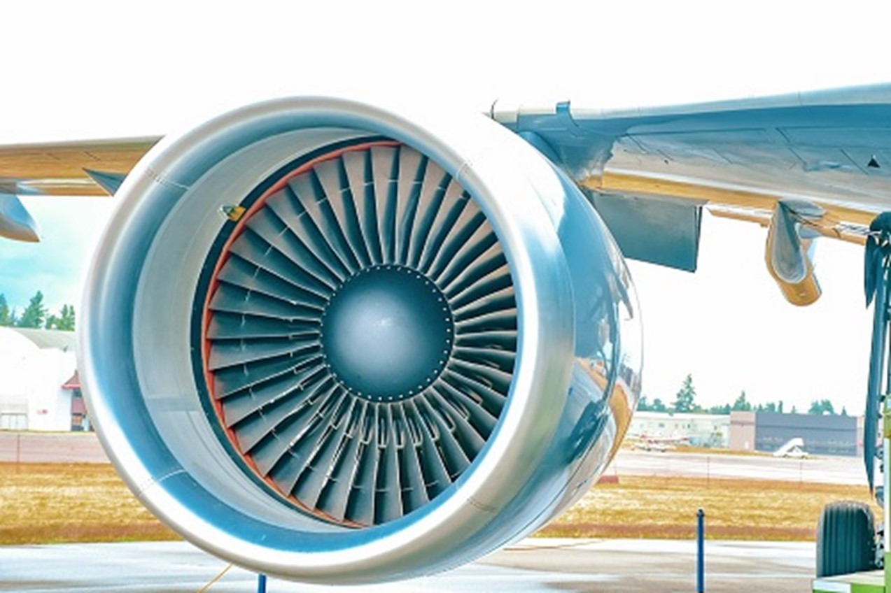 Impressive closeup photograph of an airplane’s jet engine while sitting idle on a runway on a bright day.