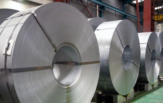 Close-up shot of a warehouse row filled with large finished and banded slit steel coils exhibiting the quality product manufactured by a high-performing metal service center like NMC.