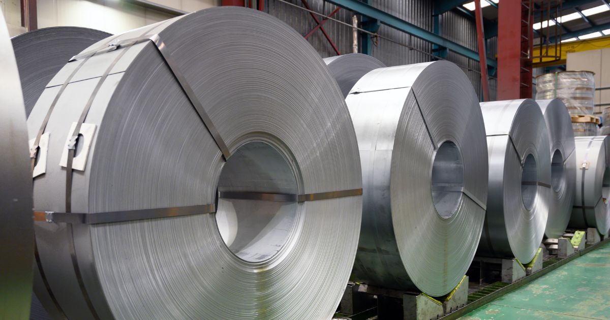 Close-up shot of a warehouse row filled with large finished and banded slit steel coils exhibiting the quality product manufactured by a high-performing metal service center like NMC.