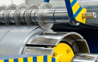 A close-up shot of a high-speed industrial slitting machine, representing vital part of the precision metal processing process.
