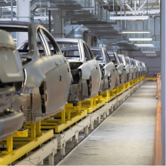NMC-2026-07-automated-car-plant Conveyer of car frames being manufactured at automated car plant, demonstrating the assembly process that occurs after OEMs secure certified flat-rolled metal from an experienced partner.